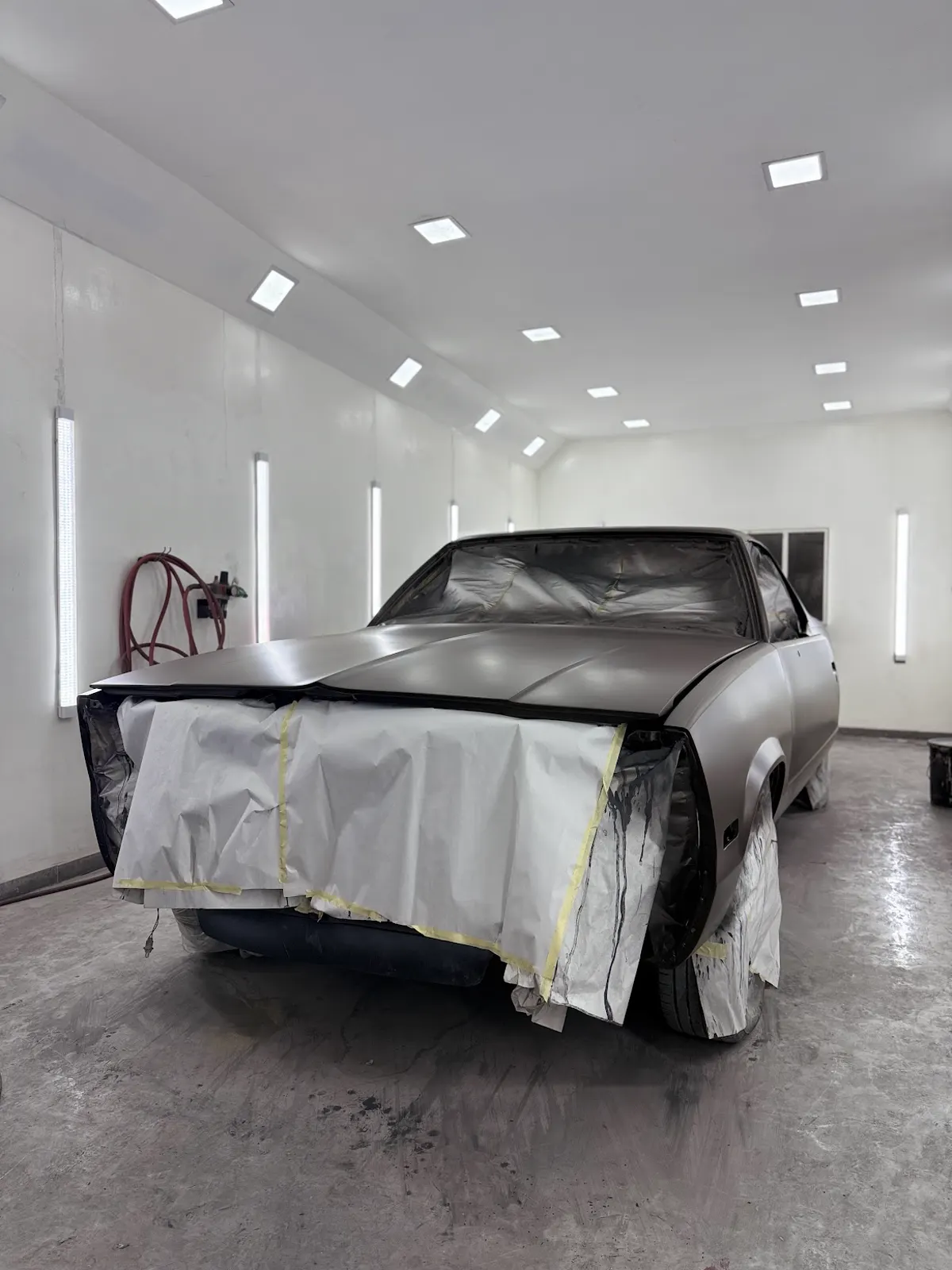 Chevrolet en fondo primer dentro de la cabina de pintura